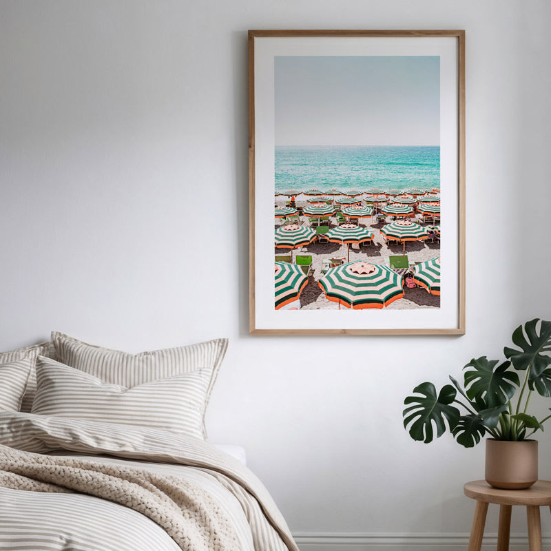 Framed artwork of a beach scene with umbrellas in a bedroom setting.