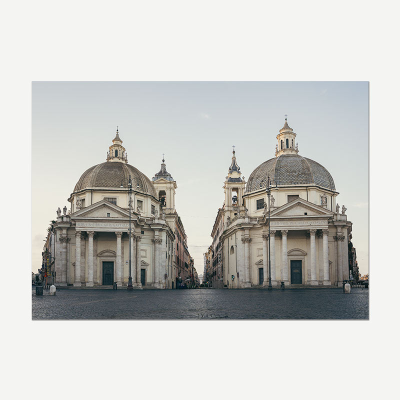 A square art print depicting a symmetrical view of two grand classical cathedral domes in a plaza, presented on a light gray background.