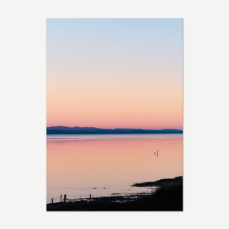 Surreal landscape with a pink sky over water and mountains