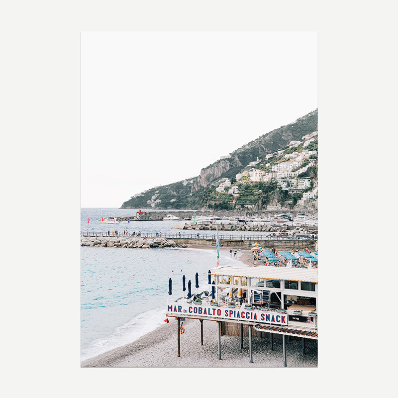 Beach scene with a mountainous background and a sign for 'Mar di Cobalto Spiaggia Snack'.