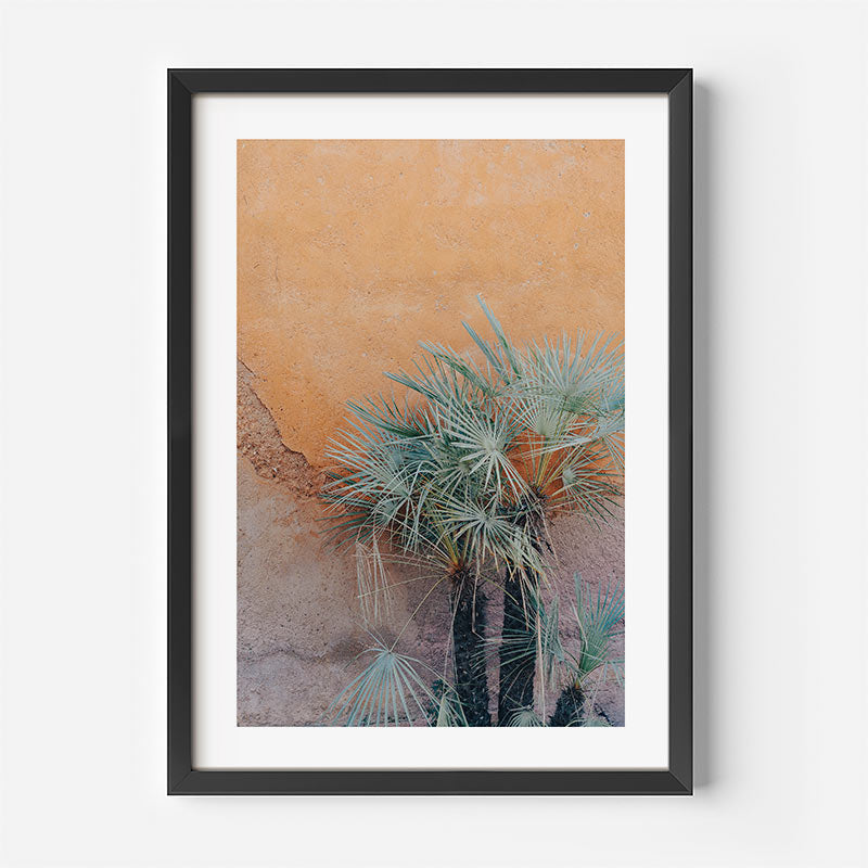 Framed artwork of a desert landscape with cacti on a white wall