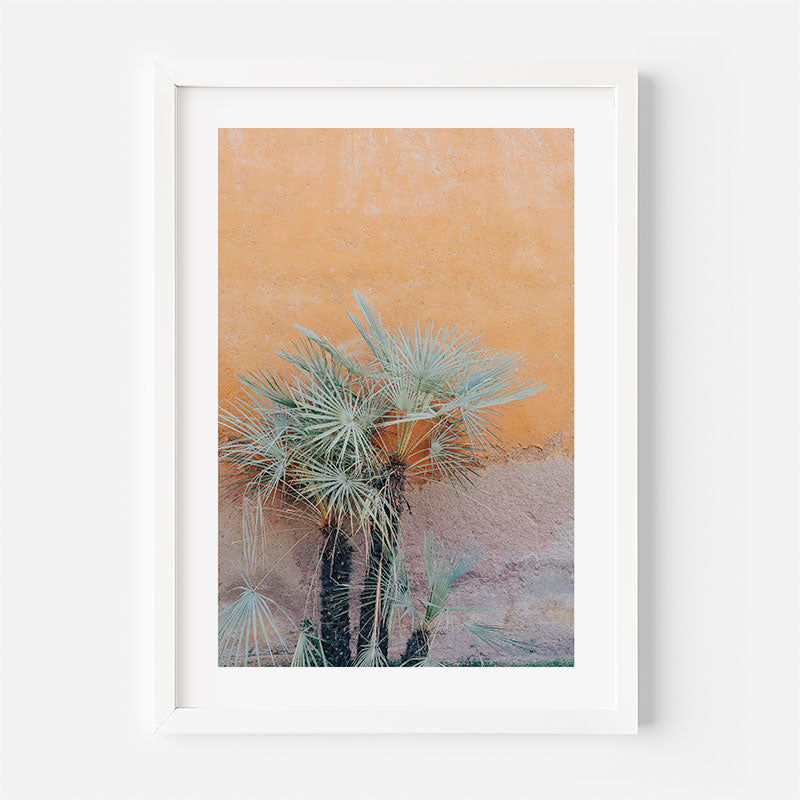 Framed artwork of a palm tree against an orange and pink textured background