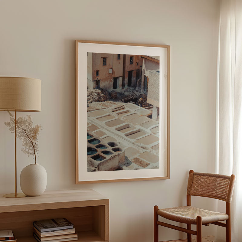 Framed artwork on a wall with a lamp and chair in a room.