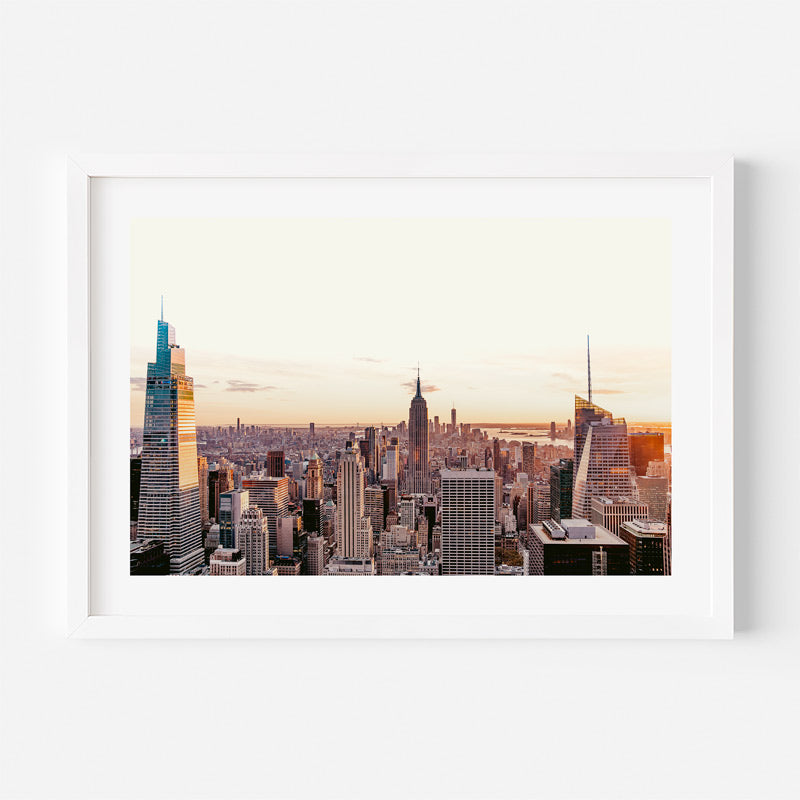 Framed cityscape print of a skyline with tall buildings at sunset.