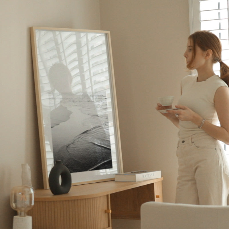 Woman standing in a room with a large framed picture on the wall