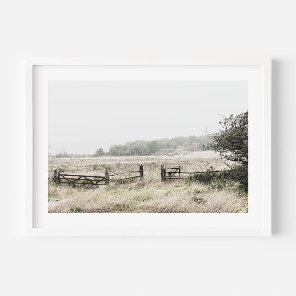 A white framed photograph of a field with a fence at East Sussex, UK