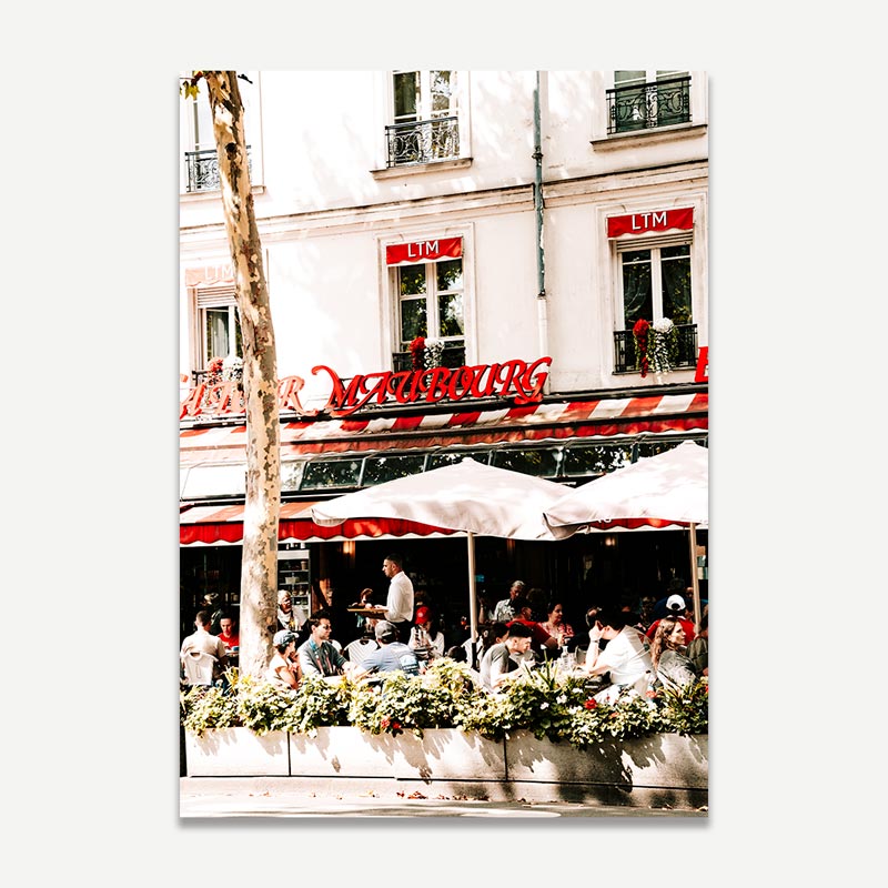 People dining outside a restaurant with a prominent sign on a building facade.
