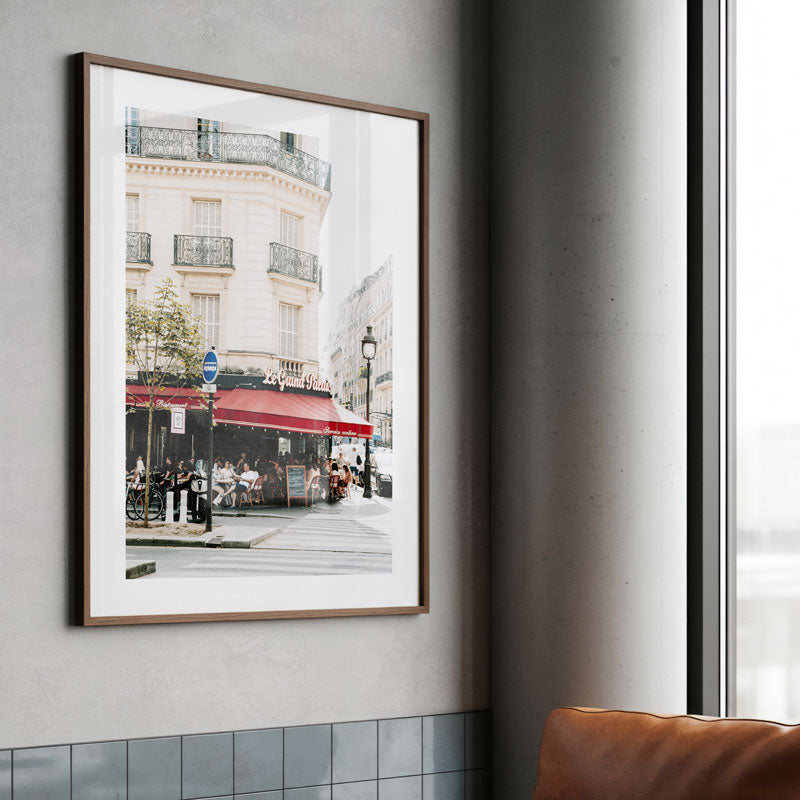 Framed photograph of a city street scene on a wall next to a window.