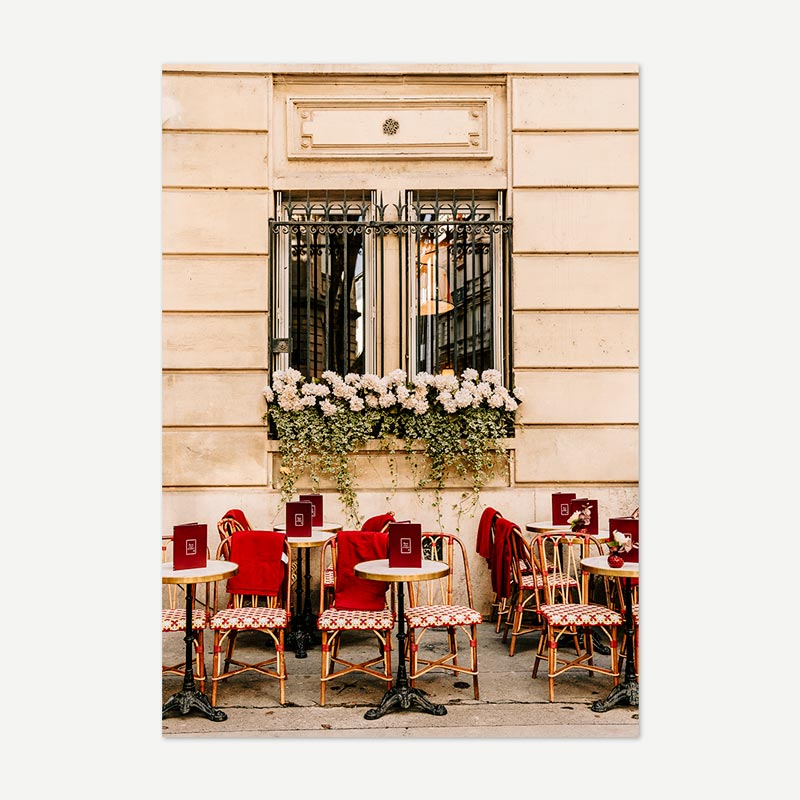 Café exterior with tables, chairs, and a flower box on a building facade.