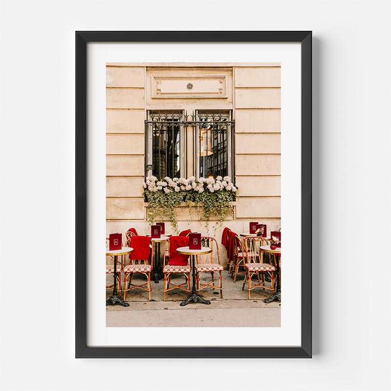 Framed photograph of a Parisian street cafe with red chairs and tables.