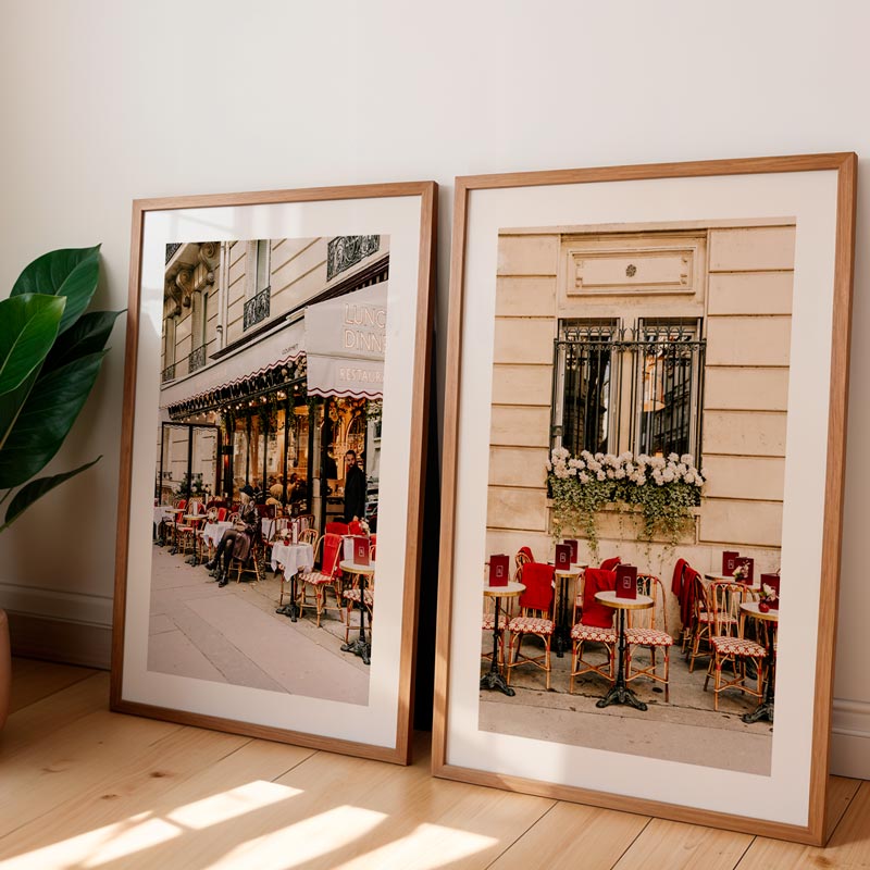 Two framed photographs of an outdoor cafe scene on a wooden floor.