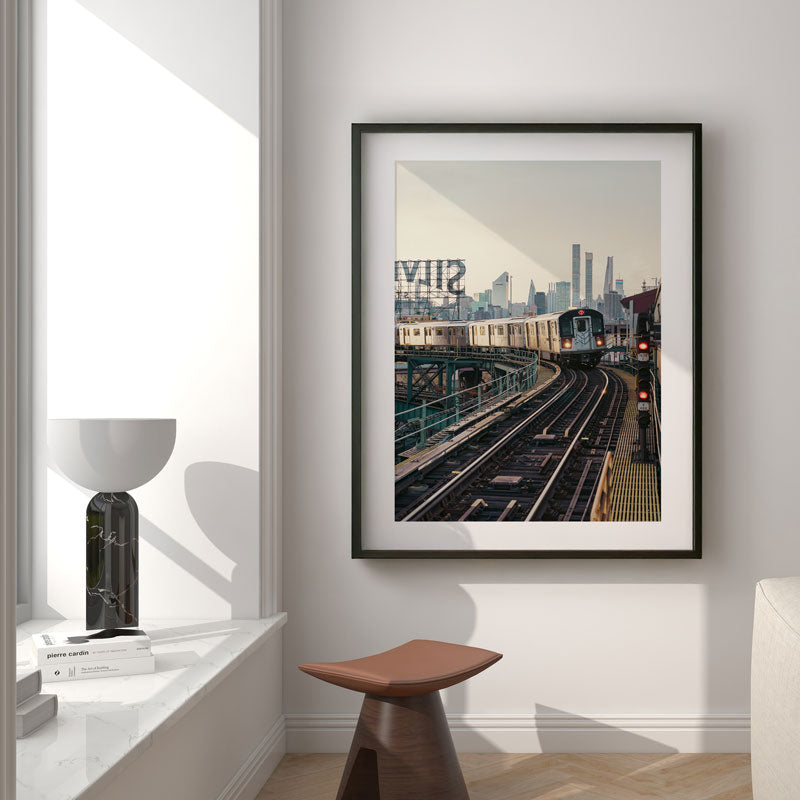 Framed photograph of a cityscape with train tracks on a wall in a modern interior setting.