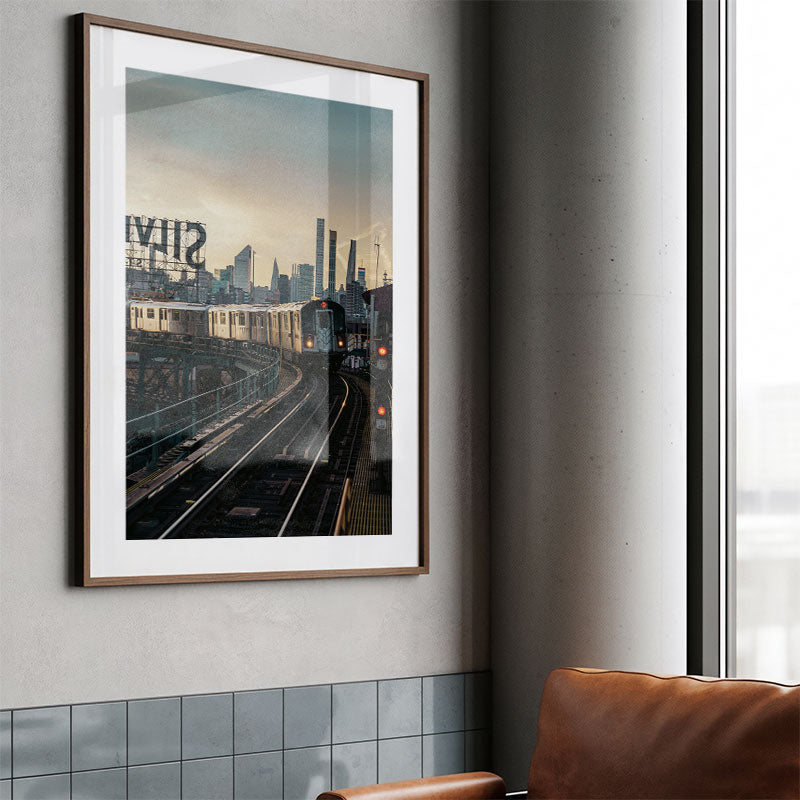 Framed cityscape print on a wall next to a window with a brown leather chair.