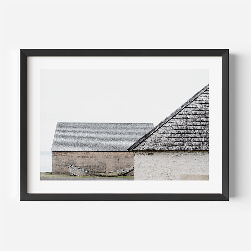 Framed photograph of a rustic building with a thatched roof on a white background