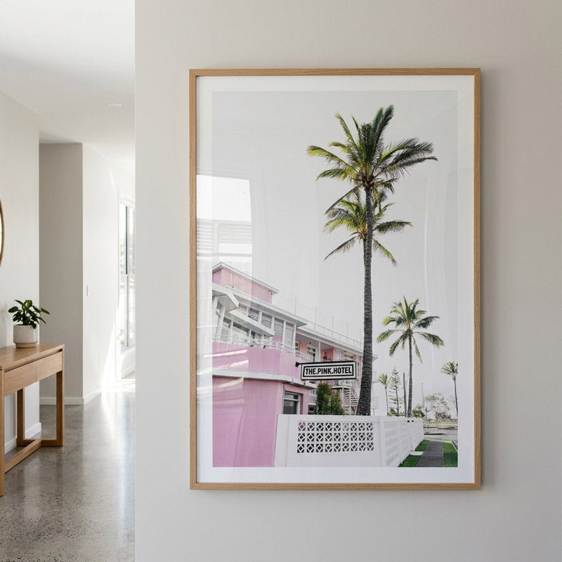 Framed photograph of a pink building with palm trees in a modern interior setting.