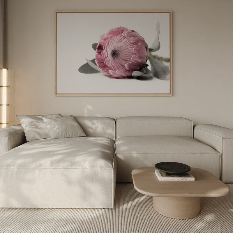 Modern living room with a beige sectional sofa, coffee table, and floral artwork on the wall.