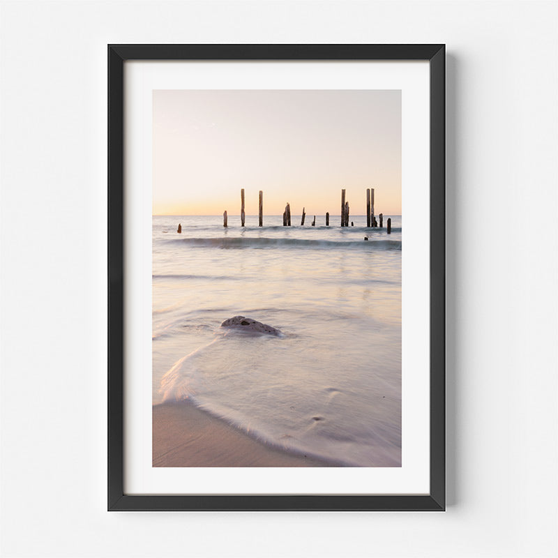 Framed photograph of a beach scene with a sunset over water and a black frame.