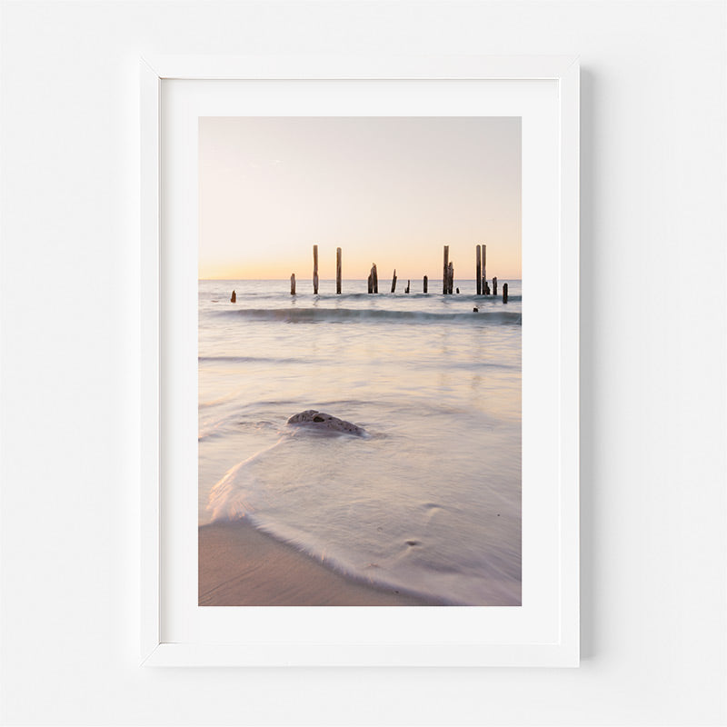 Framed photograph of a beach scene with a sunset over water and a white frame.
