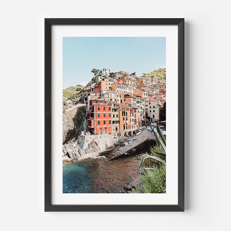 Framed photograph of a coastal town with colorful buildings on a hillside.
