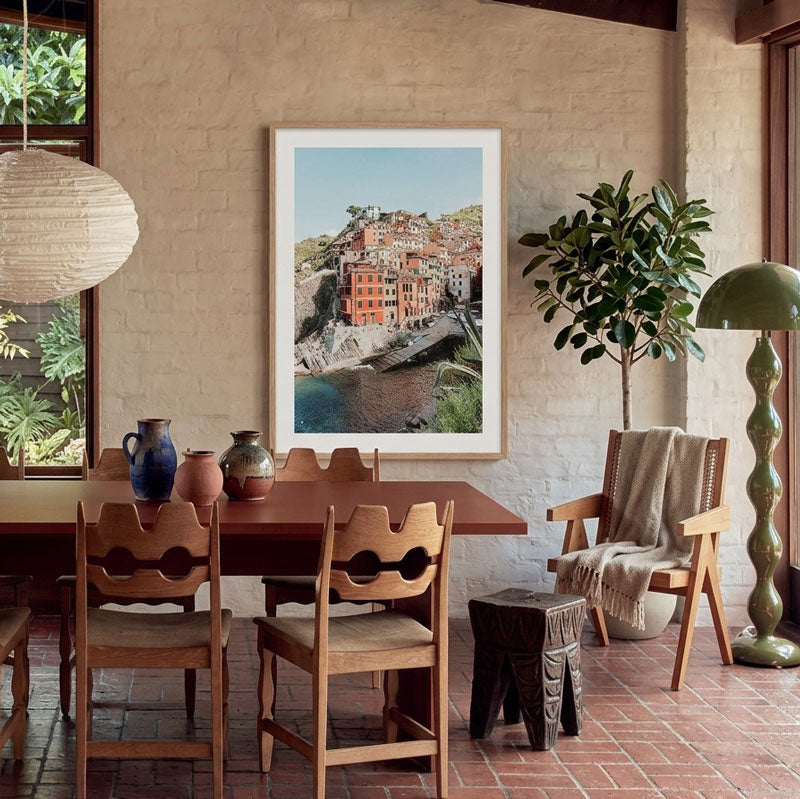 Dining room with wooden table and chairs, framed artwork on the wall, and a plant.