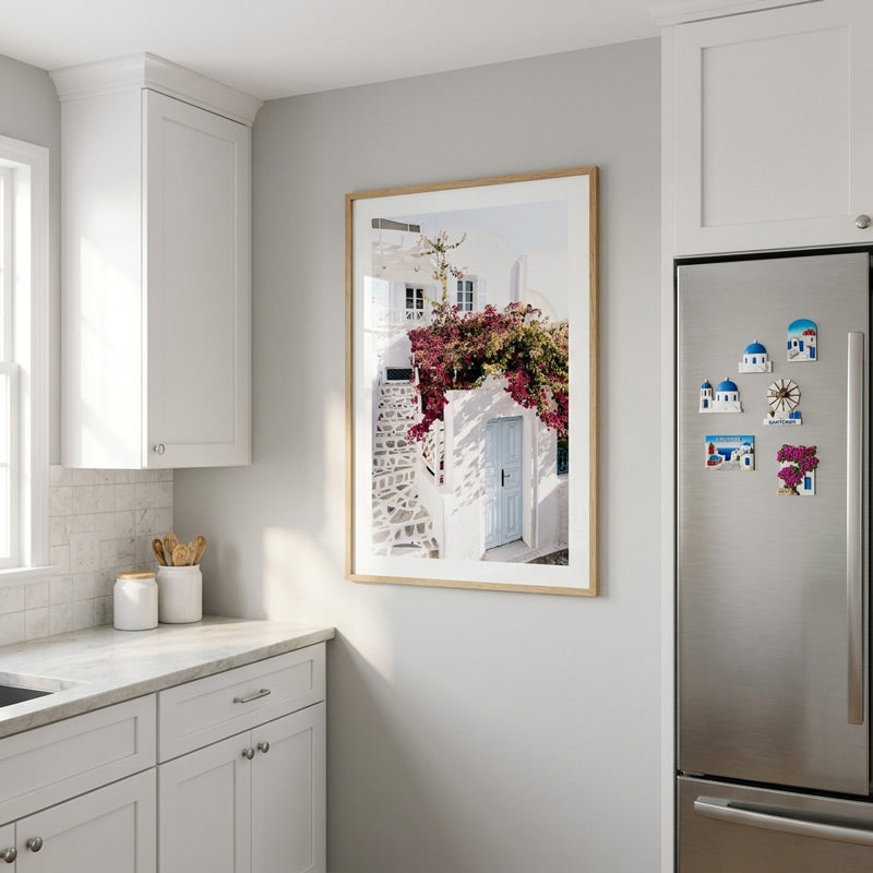 Kitchen interior with a framed picture on the wall and a refrigerator with magnets.