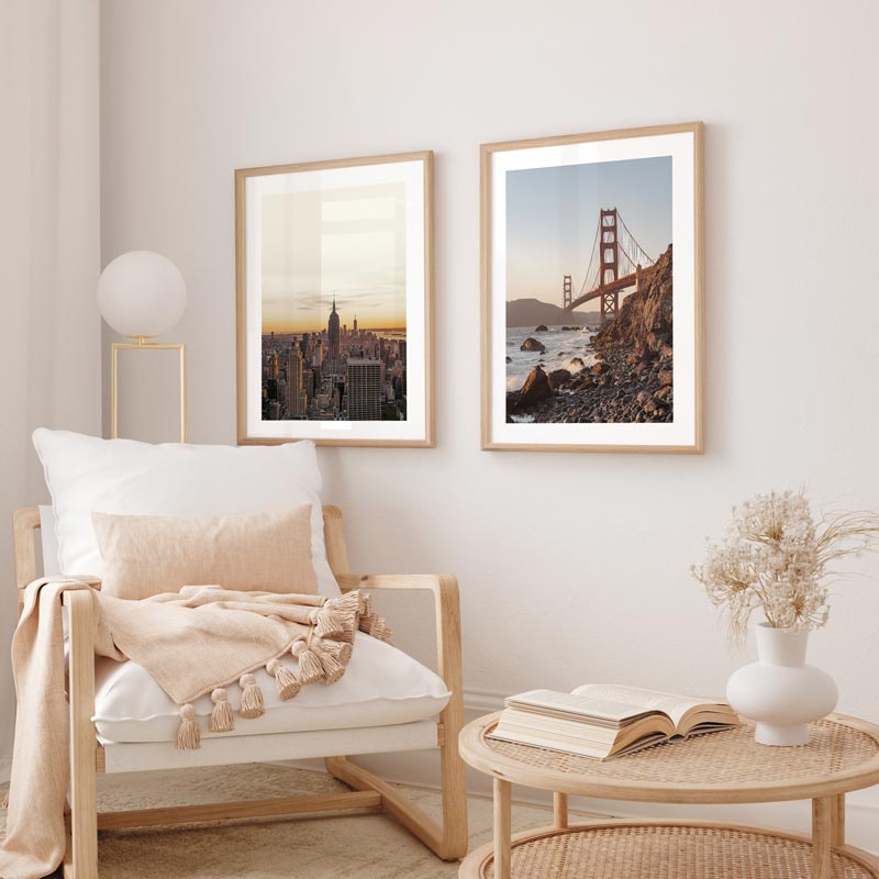 Living room with a wooden armchair, coffee table, and framed cityscape and bridge artwork on the wall.