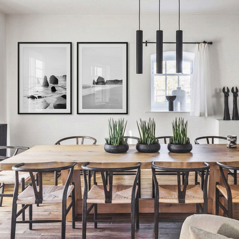 Modern dining room with wooden table and chairs, black pendant lights, and framed artwork on the wall.