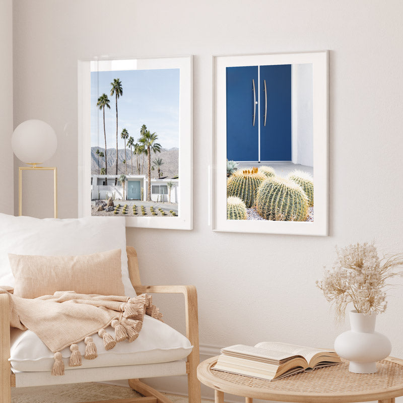 Living room with two framed artworks on the wall, a chair with a blanket, and a small table with a vase and book.