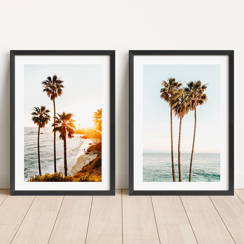 Two framed prints of palm trees by the ocean on a wooden floor.
