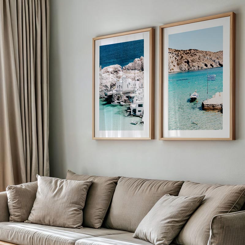 Two framed beach scenes on a wall above a beige sofa.