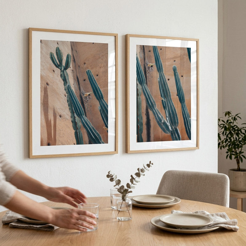 Dining room with framed cactus artwork on the wall and a person setting the table.