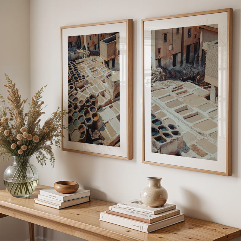 Two framed artworks on a wall above a wooden console table with decorative items.