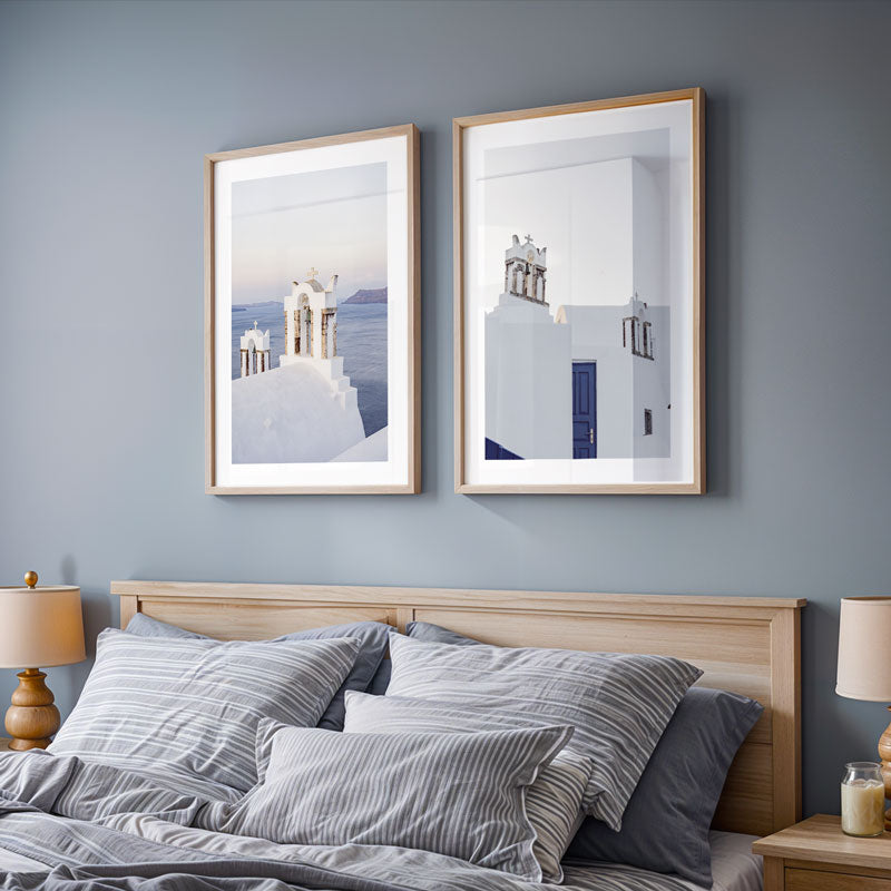 Two framed artworks on a wall above a bed with gray bedding.