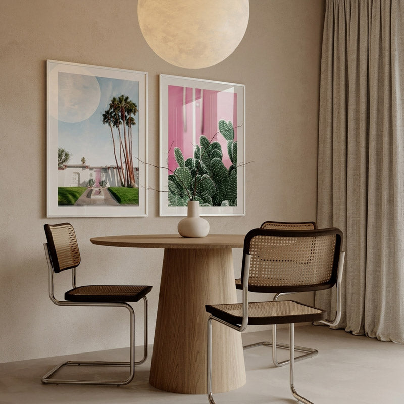 Dining room with wooden table and chairs, framed artwork on the wall, and a plant.