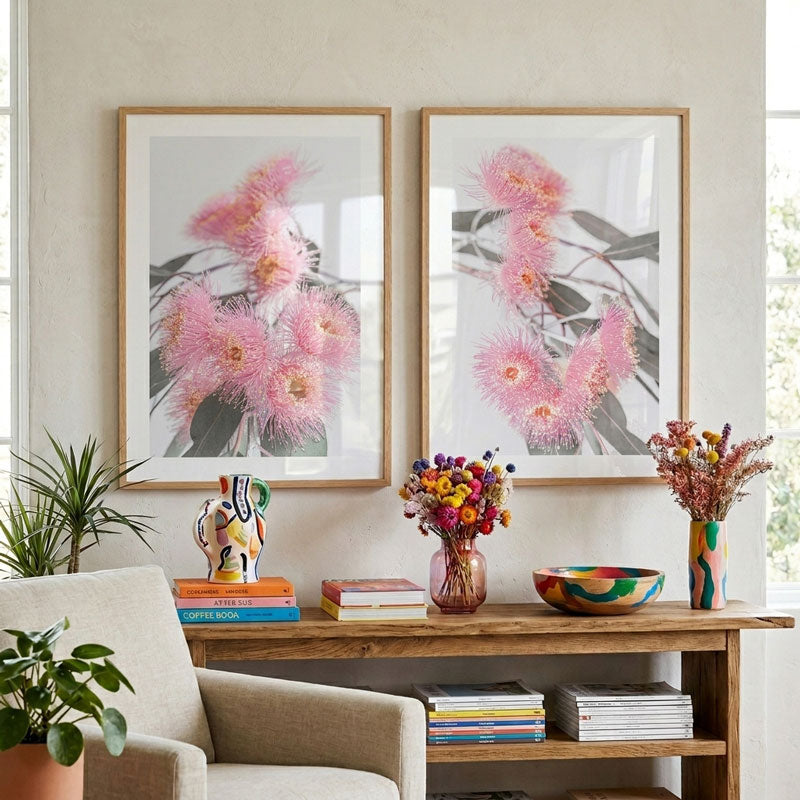 Two framed floral prints on a wall above a wooden console table with decorative items.