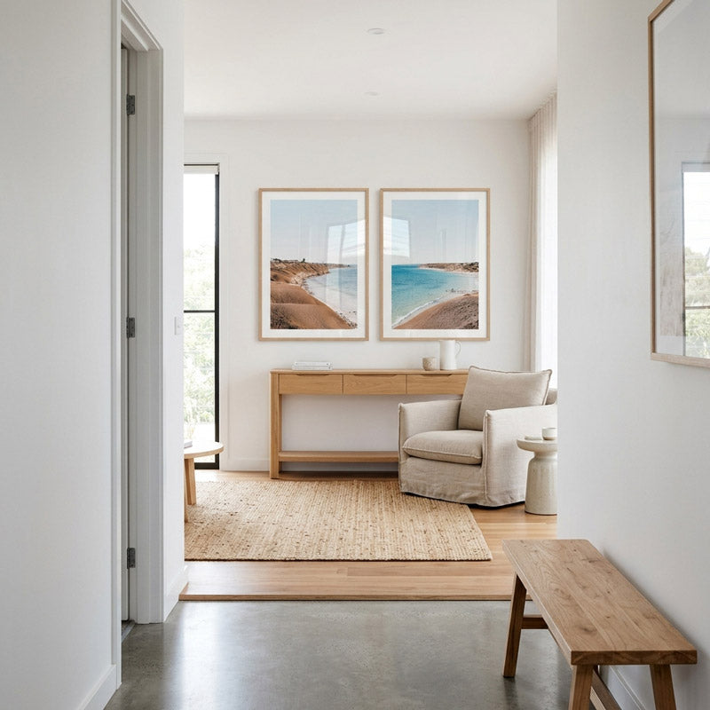 Modern living room with a beige sofa, wooden bench, and wall art depicting landscapes.