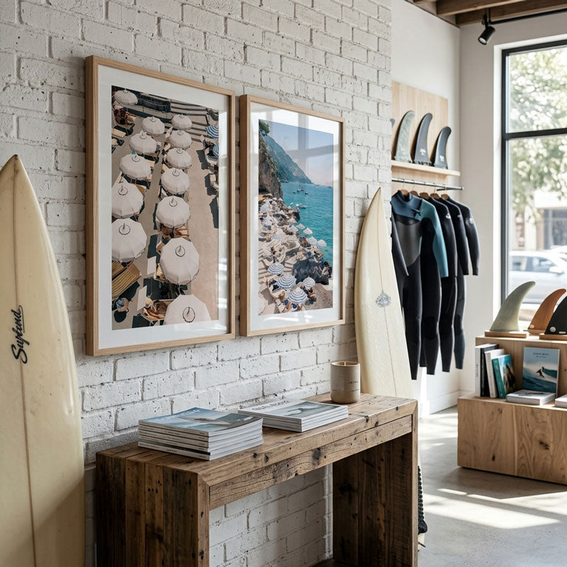 Interior of a store with framed artwork, surfboards, and wetsuits.