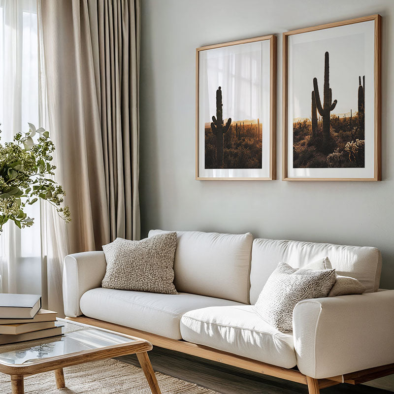 Living room with a white sofa, wooden coffee table, and two framed cactus artworks on the wall.