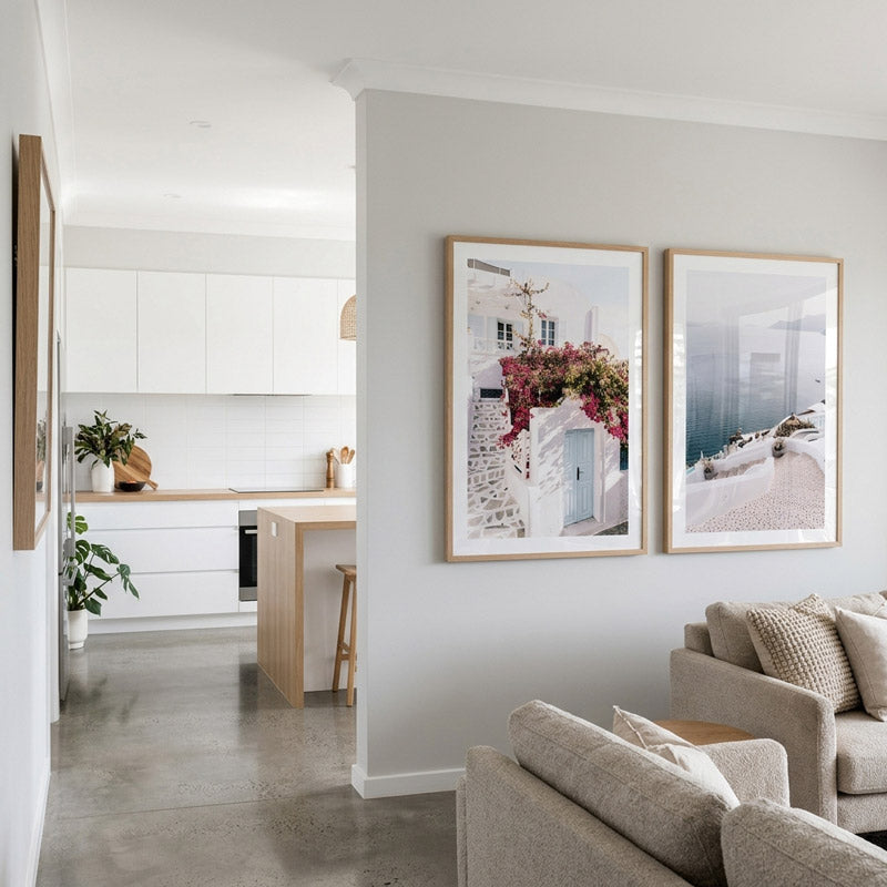 Modern living room with two framed pictures on a wall, leading to a kitchen.