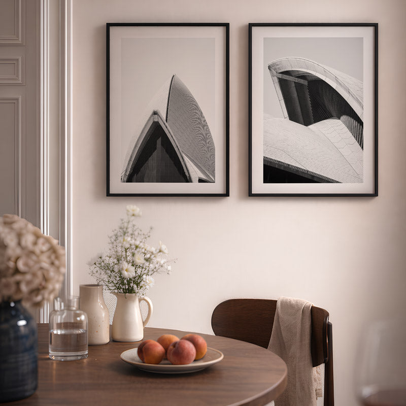 Dining room with framed black and white artworks on the wall, a table with fruits, and decorative items.
