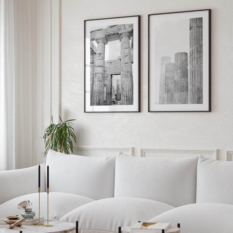 Modern living room with white sofa, framed black and white artworks on the wall, and a small plant.