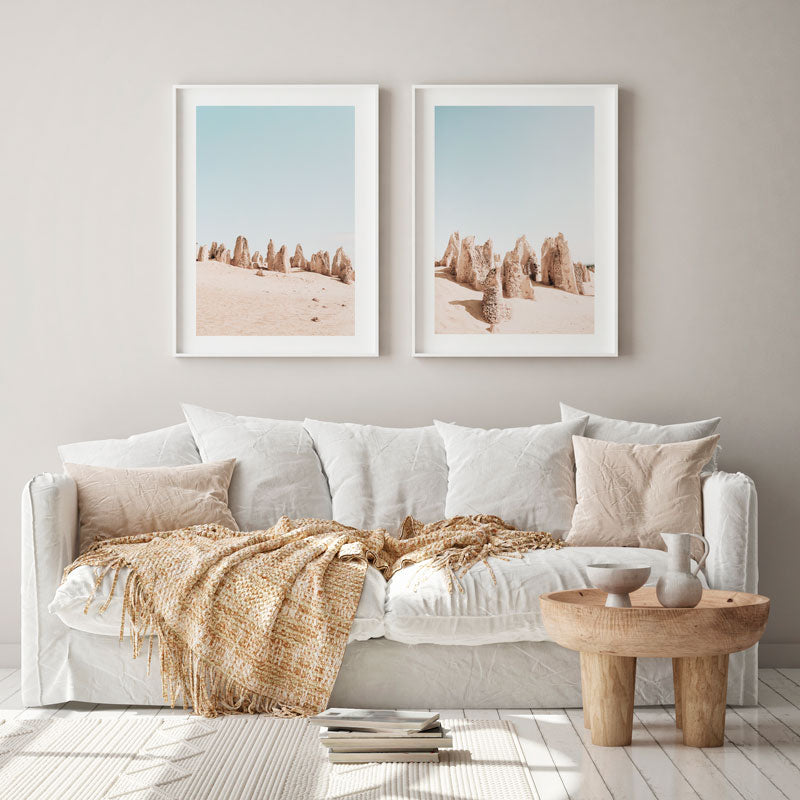Living room with a white sofa, wooden coffee table, and two framed desert landscape prints on the wall.