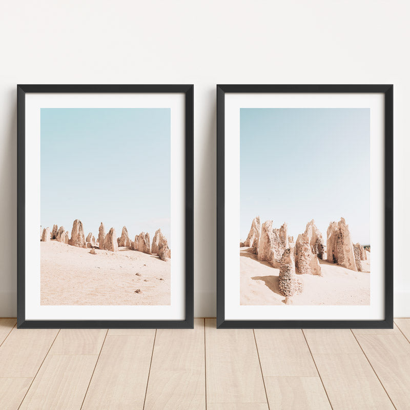 Two framed prints of desert landscape with rock formations on a wooden floor.