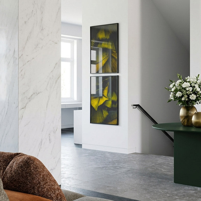 Modern interior with a marble wall, artwork on the wall, and a vase with flowers on a table.