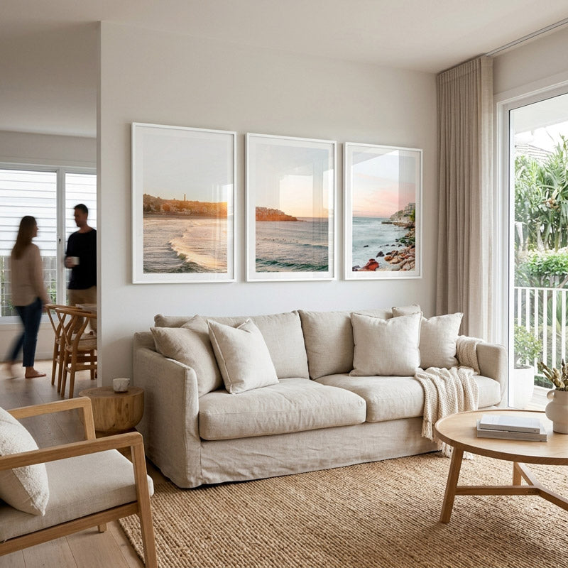 Living room with beige sofa, wooden coffee table, and wall art of beach scenes.