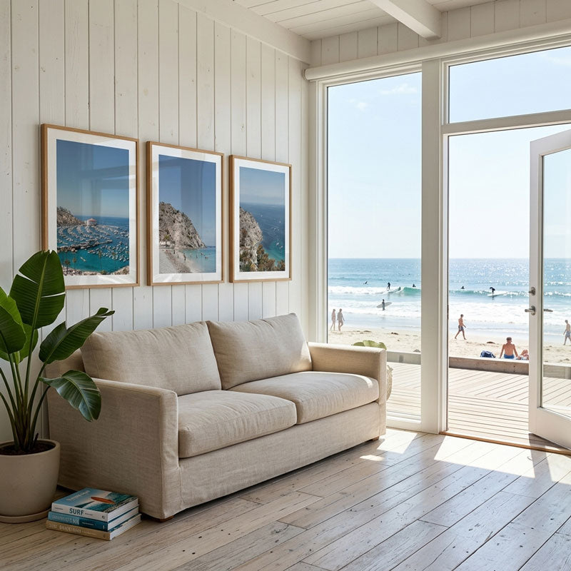 Beige sofa in a room with large windows overlooking a beach.
