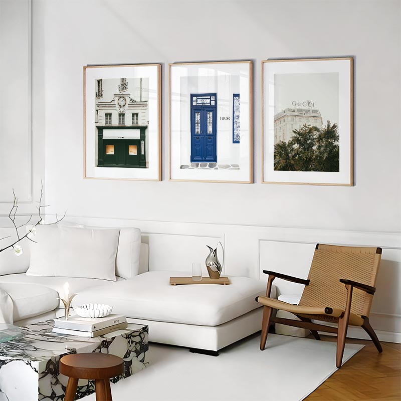 Modern living room with a white sofa, wooden chair, and framed pictures on the wall.