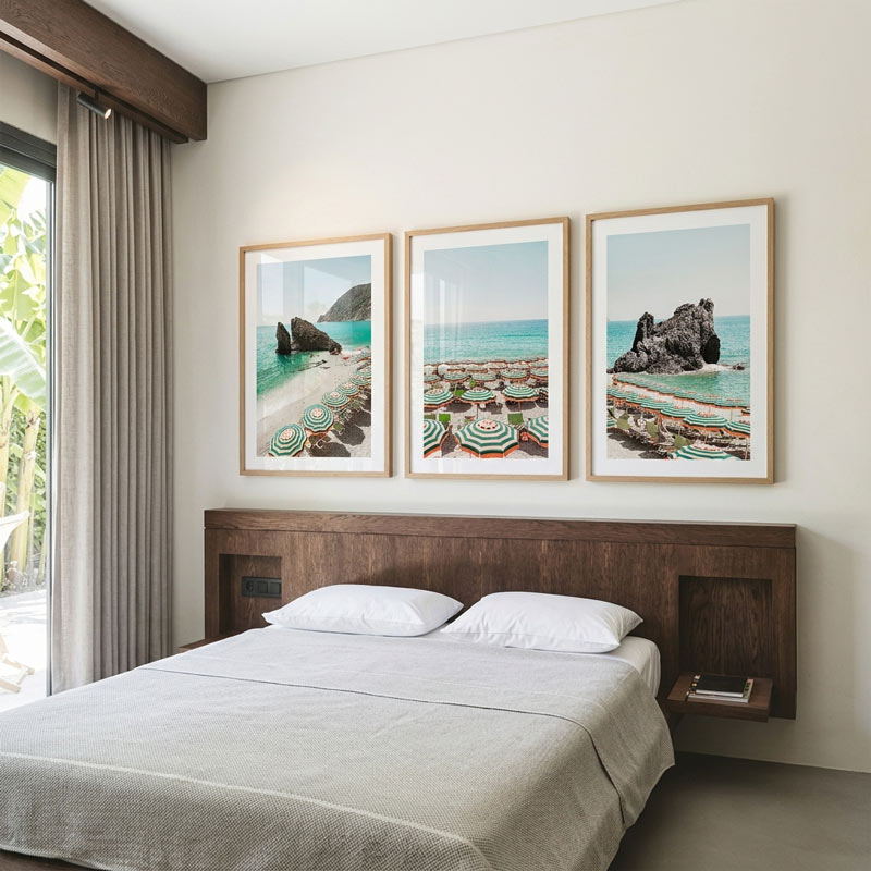 Bedroom with a wooden headboard and three framed beach scenes on the wall.