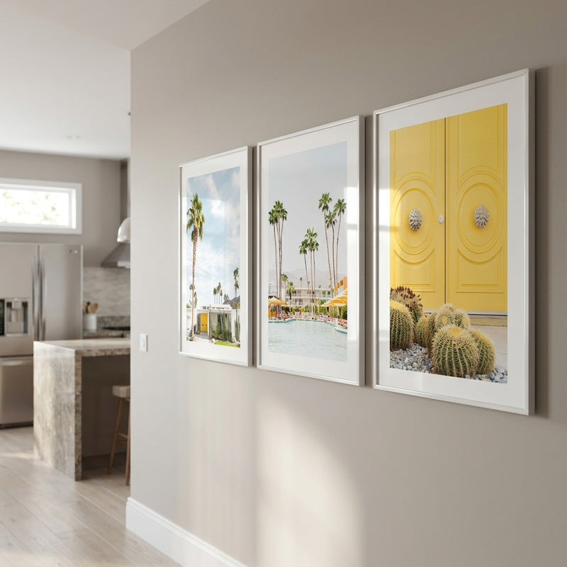Three framed artworks on a wall in a modern kitchen setting.