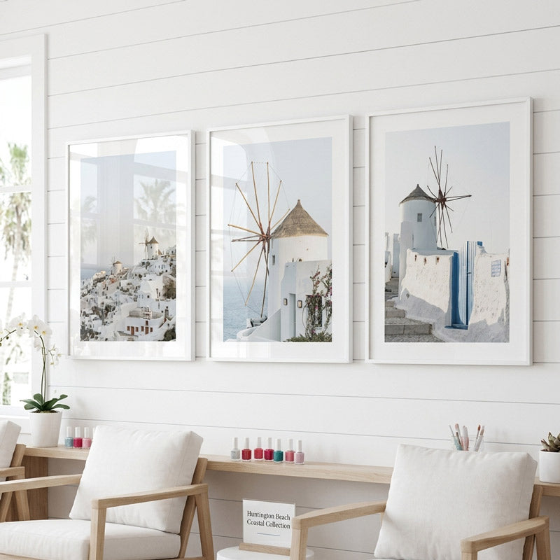 Three framed artworks of windmills and Mediterranean architecture on a white wall.